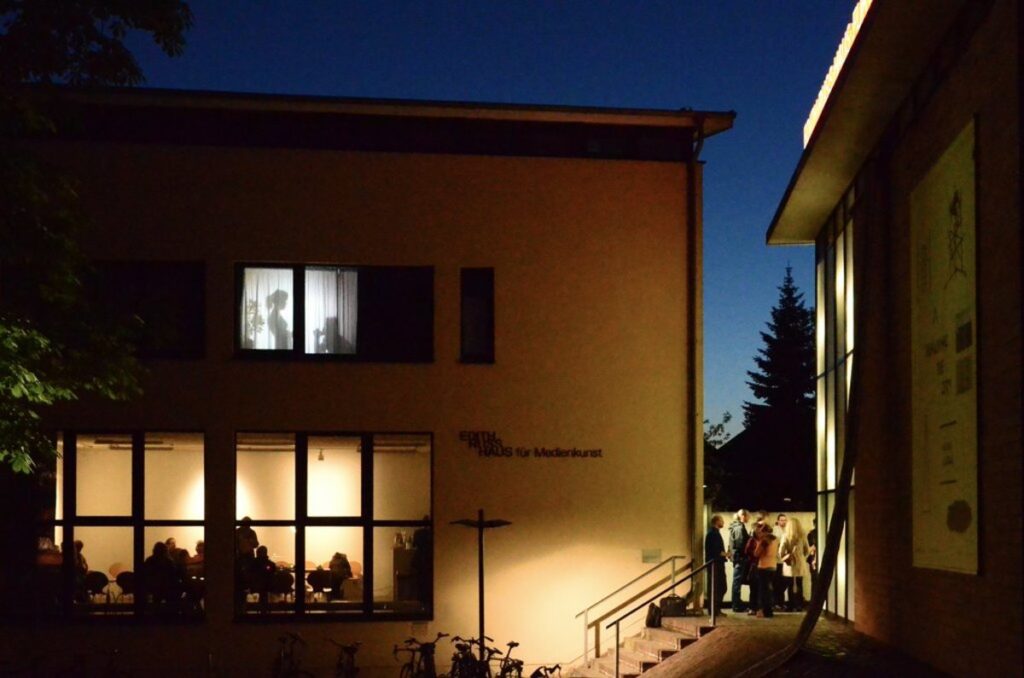 Opening Repairing the City, 2015. The work Voyeur by Nevin Aladag can be seen at the top of the window.   